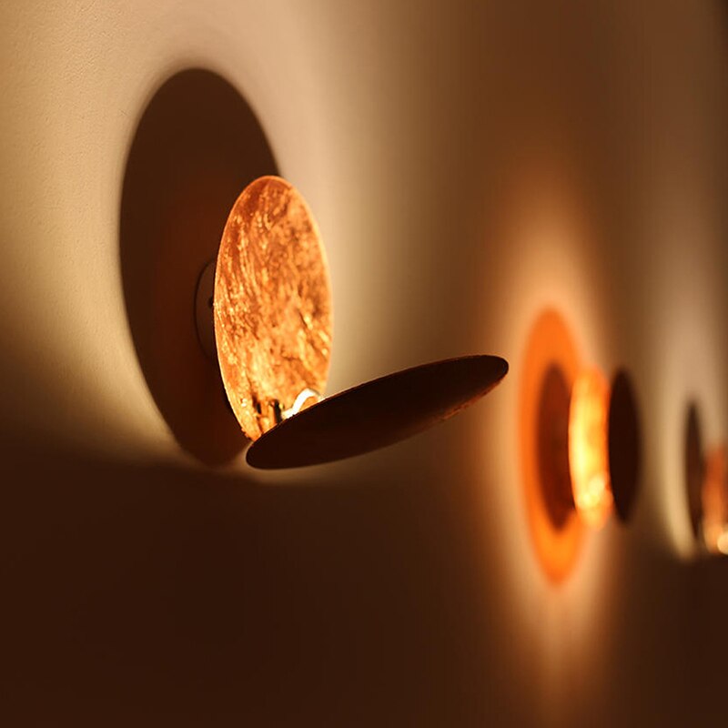 Gold eclipse-inspired LED wall light with rotating disc