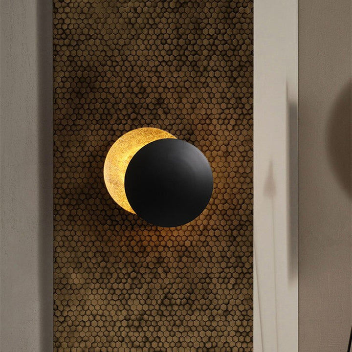 Gold eclipse-inspired LED wall light with rotating disc