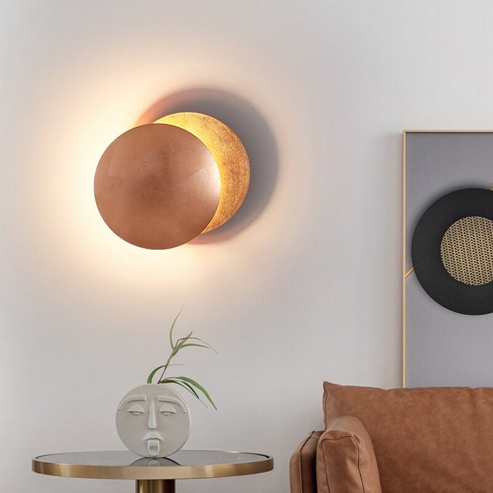 Gold eclipse-inspired LED wall light with rotating disc