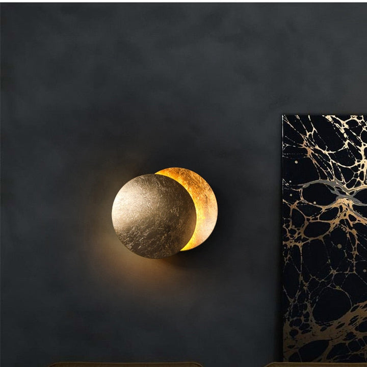 Gold eclipse-inspired LED wall light with rotating disc